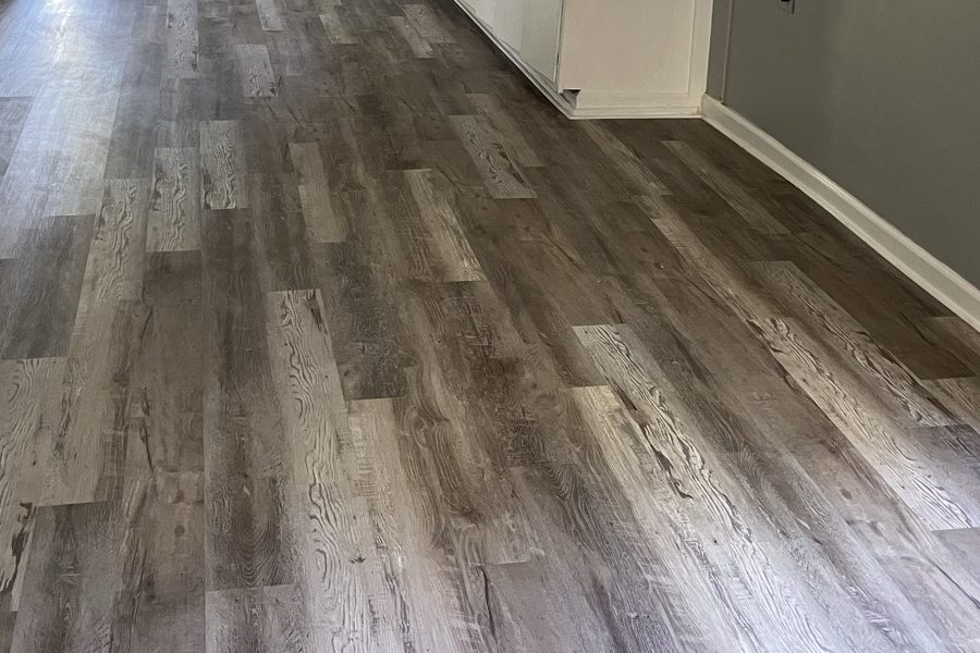 Grey luxury vinyl plank flooring through an open kitchen and living area